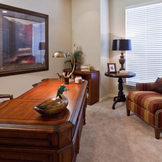 A cozy home office with a wooden desk, comfortable armchair, and ambient lighting.