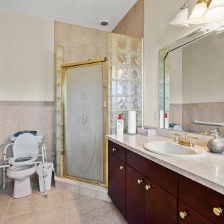 A well-lit bathroom with a glass shower, sink, and mirror.