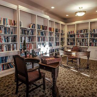 A cozy library with bookshelves, a desk, and chairs for reading.