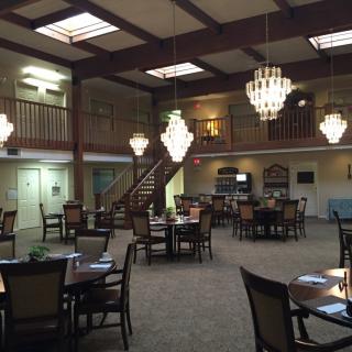 A spacious dining area with elegant chandeliers and arranged seating.