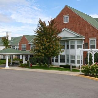A brick residential building with green roofs and a landscaped entrance.