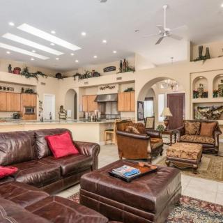Spacious open floor plan living room with modern leather furniture and adjacent kitchen.