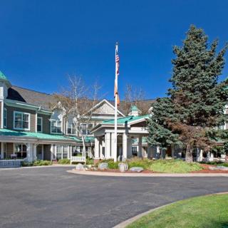 A scenic view of a hotel entrance with well-maintained landscaping and clear skies.