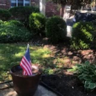 A well-maintained garden with a potted plant featuring an American flag.