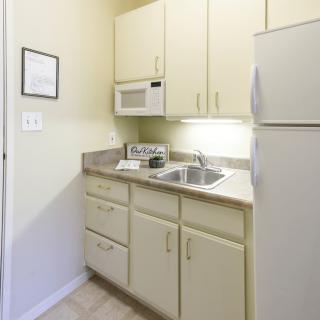 Compact apartment kitchen with cabinetry and appliances.