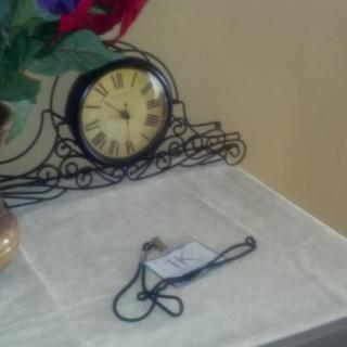 A decorative clock and floral arrangement on a table with a cord laid out.
