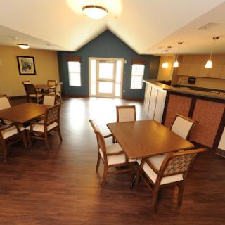 A welcoming dining area featuring wooden tables and chairs, illuminated by soft lighting.