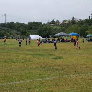 A youth soccer game in progress on a cloudy day.