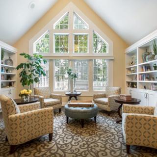 A cozy living room with large windows, bookshelves, and comfortable seating.