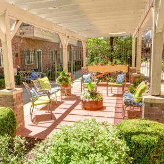 A cozy outdoor patio with a pergola, featuring comfortable seating and vibrant plants.