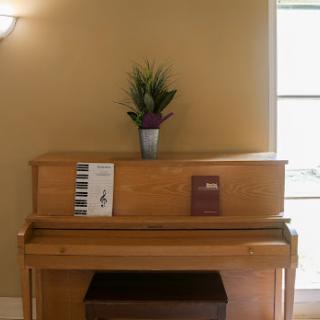 A wooden piano adorned with a decorative plant and sheet music, creating a cozy indoor ambiance.