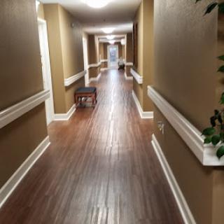 A well-lit hallway featuring wooden flooring and warm brown walls.