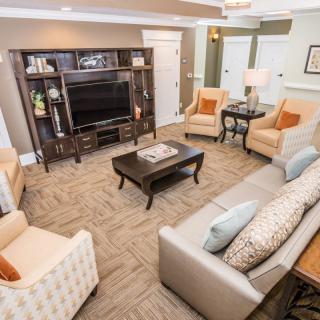 A cozy and well-furnished living room featuring a television, sofa, armchairs, and a coffee table.