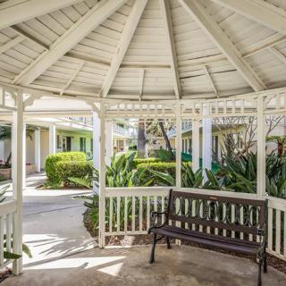 A peaceful gazebo with a bench surrounded by lush garden greenery.