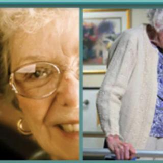 An elderly woman wearing glasses and a sweater is sitting indoors on a wheelchair.