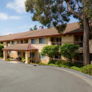 A two-story residential building with surrounding trees and a driveway.