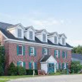 A traditional brick house with multiple dormer windows and a well-maintained garden.