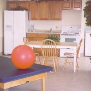 A kitchen area with a dining table and an exercise ball on a bench.