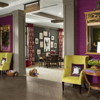 A vibrant living room interior featuring colorful furniture, framed artwork, and eclectic decor.