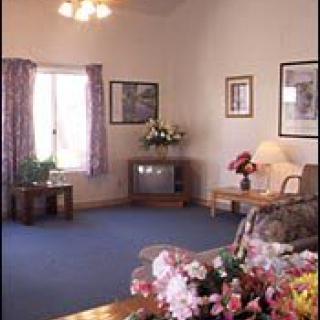 A cozy living room with a sofa, television, and floral decorations.