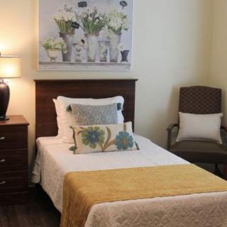 A cozy bedroom with a single bed, decorative pillows, and a floral painting on the wall.