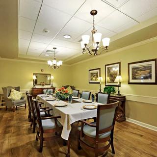 An elegantly set dining room with a long table, surrounded by chairs and decorated with artwork on the walls.