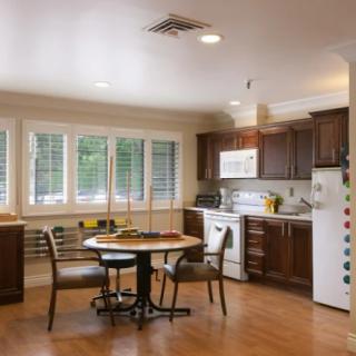 A cozy kitchen with a dining area featuring wooden floors, cabinets, and a round table with chairs.