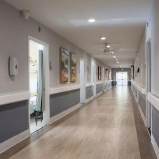 A long, well-lit hallway with doors and artwork on the walls.