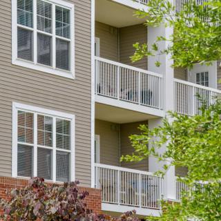 A residential apartment building with balconies and surrounding trees.