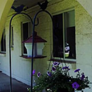 A cozy porch with hanging flowers and a bird feeder.