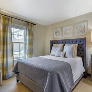 A cozy bedroom with a neatly made bed, elegant curtains, and wall art.