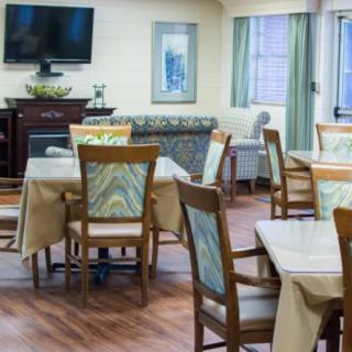 A cozy dining area with neatly arranged tables and chairs, featuring a television on the wall.