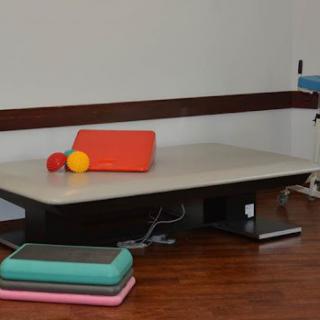 A physical therapy room featuring a low table and colorful mats.