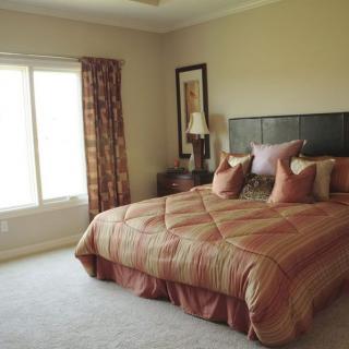 A cozy bedroom with a king-sized bed, pillows, and patterned curtains.
