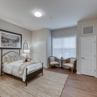 A modern and cozy bedroom featuring a comfortable bed, two chairs by the window, and stylish decor.