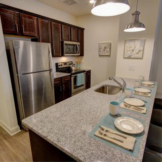 A modern kitchen with stainless steel appliances, granite countertops, and bar seating.