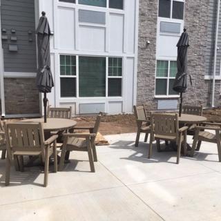 Outdoor patio area with tables, chairs, and umbrellas next to a building.