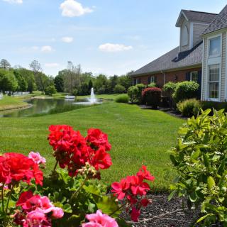 A picturesque garden with vibrant flowers and a tranquil pond in front of a house.