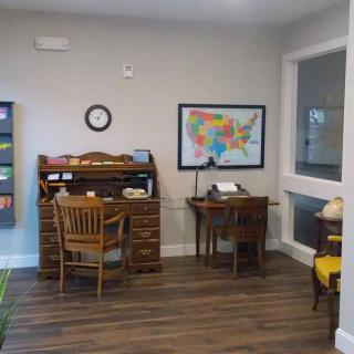 A room with vintage decor featuring old-fashioned desks, a typewriter, and a map of the USA on the wall.