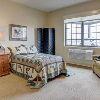 A cozy bedroom interior with a bed, nightstand, and large window.