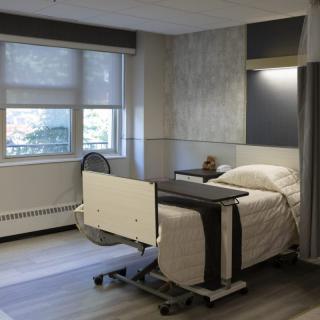 A clean and modern hospital room with a single bed by the window.