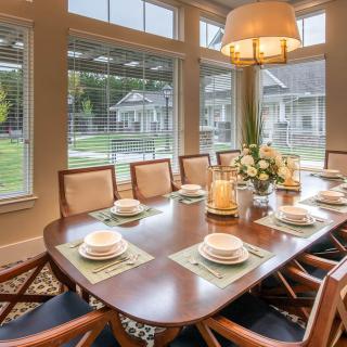 A stylish dining room with a set table and large windows offering a view outside.