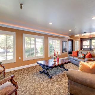 A cozy living room with comfortable seating, a large coffee table, and ample natural light streaming through multiple windows.