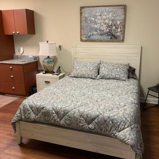 A cozy bedroom with a neatly made bed, nightstand and decorative elements.