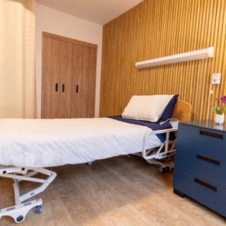 A modern hospital room with a neatly made bed and stylish wood paneling.