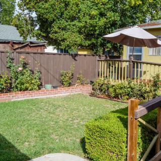 A cozy backyard with a grassy lawn, wooden deck, and shaded umbrella.