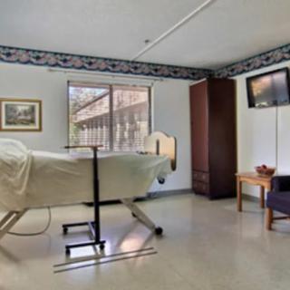 A hospital room with a single bed, television, and minimalist furnishings.