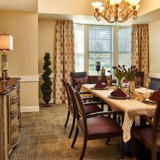 A warmly decorated dining room with a set table, chandelier, and elegant furnishings.