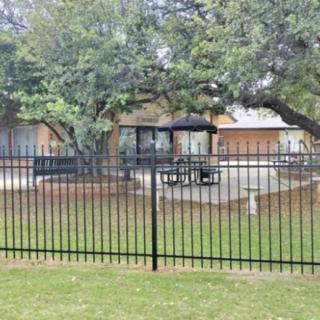 A suburban house with a fenced patio area, outdoor furniture, and surrounding trees.