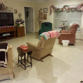 A cozy living room with chairs and a television, decorated for the holidays.